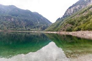 alpina hög berg sjö, barr- trän är reflekterad i de vatten, antrona dal campliccioli sjö, Italien piedmont foto