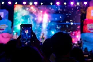 person använder sig av mobil smartphone tar Foto festival musik konsert.