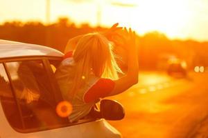 Lycklig kvinna flicka går till sommar resa resa i bil. foto