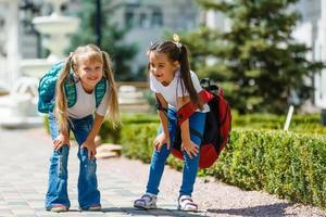 två liten skol med tung ryggsäckar gå till skola foto