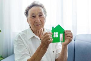 senior kvinna innehar de layout av de hus i henne händer foto