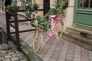 gammal rosa cykel utrustad med korg av blommor dekoration foto