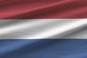 nederländerna flagga med stor veck vinka stänga upp under de studio ljus inomhus. de officiell symboler och färger i baner foto