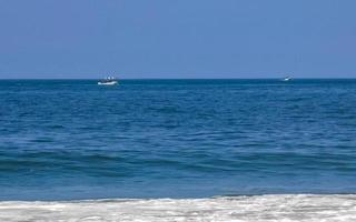 Sol strand människor vågor och båtar i puerto escondido Mexiko. foto