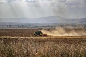 de traktor förbereder de jord för sådd och odling. lantbruk och agronomi begrepp. foto