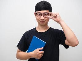 stilig man bär glasögon gest självsäker innehav blå anteckningsbok foto