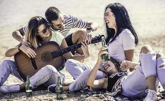 sommar, högtider, semester, musik, Lycklig människor begrepp - grupp av vänner med gitarr har roligt på de strand foto