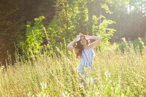 ung kvinna gående bland vild på solig sommar dag. begrepp av de glädje av kommunicerar med sommar natur foto