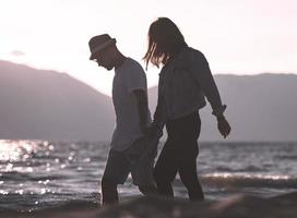 Lycklig romantisk par njuter skön solnedgång promenad på de strand. resa semester pensionering livsstil begrepp foto