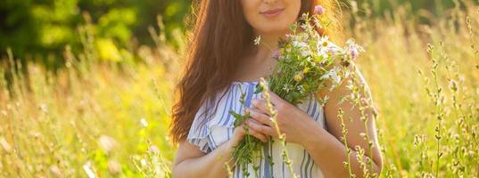 ung kvinna plockning blommor i de äng i sommar kväll foto