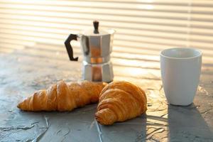 frukost med croissant på skärande styrelse och svart kaffe. morgon- måltid och frukost begrepp. foto