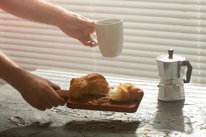 frukost med croissant på skärande styrelse och svart kaffe. morgon- måltid och frukost begrepp. foto