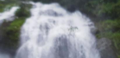 suddig vattenfall med grön träd, skog bakgrund på thailand. naturlig tapet i tropisk djungel begrepp. foto