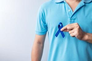 mars månad för medvetenhet om kolorektal cancer, kvinna som håller mörkblått band för att stödja människor som lever och sjukdom. hälsovård, hopp och världen cancer dag koncept foto