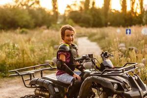 de liten flicka rider en quad cykel atv. en mini quad cykel är en Häftigt flicka i en hjälm och skyddande Kläder. elektrisk quad cykel elektrisk bil för barn populariserar grön teknologi. foto