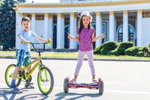 flicka på en cykel och en pojke på en gyroskop är ridning tillsammans foto