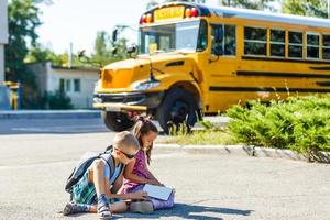 skrattande leende caucasian pojke studerande unge med rolig ansikte uttryck gående nära gul buss på 1 september dag. utbildning och tillbaka till skola begrepp. barn elev redo till lära sig och studie. foto