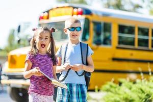 leende barn stående i främre av skola buss foto