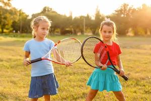två liten flickor med tennis racketar foto