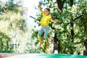 liten barn Hoppar på stor trampolin - utomhus- i bakgård foto