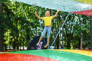 liten barn Hoppar på stor trampolin - utomhus- i bakgård foto