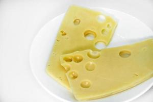 bitar av ost med hål på en vit tallrik. skivor av ost med stor hål. utsökt ost på en tallrik. foto
