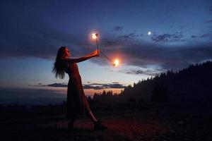 kvinna håller på med en brand visa på natt utomhus foto