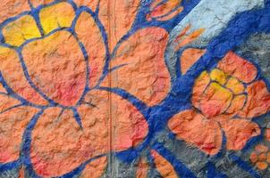 fragment av graffiti ritningar. de gammal vägg dekorerad med måla fläckar i de stil av gata konst kultur. orange blomma foto