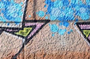 fragment av graffiti ritningar. de gammal vägg dekorerad med måla fläckar i de stil av gata konst kultur. färgad bakgrund textur i värma toner foto