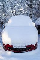 en bil helt och hållet täckt med tjock snö efter en snöstorm. foto