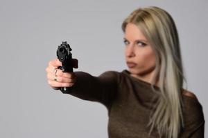 ung skön sexig blond kvinna innehav handeldvapen i hand foto
