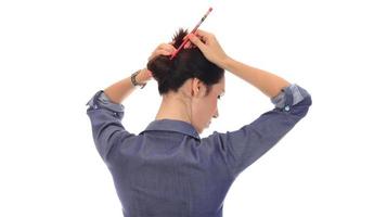 en kvinna gör en rörig hår bulle på henne huvud foto
