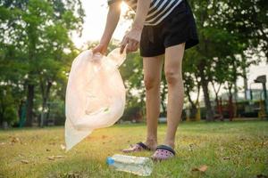 spara värld. volontär- plocka upp skräp på de parkera. människor samla svårnedbrytbara plast flaskor till förhindra skada till djur. jord dag, miljö dag. grönare de planet och minska global uppvärmningen foto