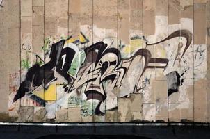 en fragment av detaljerad graffiti av en teckning tillverkad med aerosol målarfärger på en vägg av betong kakel. bakgrund bild av gata konst i brun och grädde toner foto