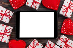 digital läsplatta tom skärm med gåva låda och hjärtan dekor på trä- tabell. topp se. valentines dag begrepp bakgrund foto