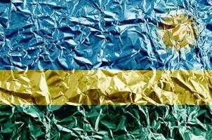 rwanda flagga avbildad i måla färger på skinande skrynkliga aluminium folie närbild. texturerad baner på grov bakgrund foto