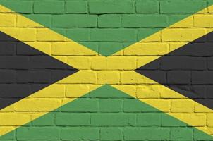 jamaica flagga avbildad i måla färger på gammal tegel vägg. texturerad baner på stor tegel vägg murverk bakgrund foto