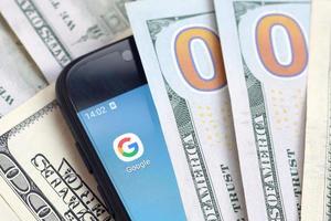 smartphone skärm med Google app och massa av hundra dollar räkningar. företag och social nätverkande begrepp foto