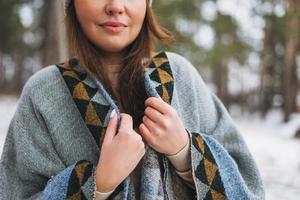 ung brunett skön kvinna i hatt och grå poncho i de vinter- skog foto