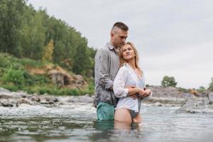 Lycklig ung par i kärlek resenärer kissing i de berg flod foto