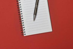 en anteckningsbok med en tom sida och en penna vilar på den foto