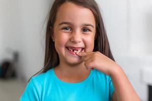 liten flicka först tand saknas på en vit bakgrund foto