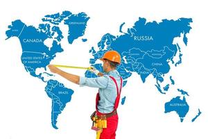 arbetstagare i hård hatt mäta med linjal värld Karta bakgrund. foto