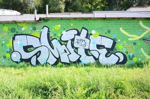 fragment av graffiti ritningar. de gammal vägg dekorerad med måla fläckar i de stil av gata konst kultur. färgad bakgrund textur i grön toner foto