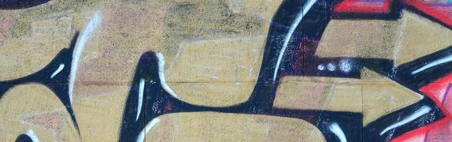 fragment av graffiti ritningar. de gammal vägg dekorerad med måla fläckar i de stil av gata konst kultur. färgad bakgrund textur i värma toner foto