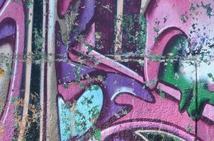 fragment av graffiti ritningar. de gammal vägg dekorerad med måla fläckar i de stil av gata konst kultur. färgad bakgrund textur i lila toner foto
