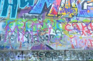 fragment av graffiti taggar. de gammal vägg är bortskämd med måla fläckar i de stil av gata konst kultur foto