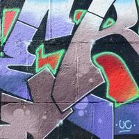 fragment av graffiti ritningar. de gammal vägg dekorerad med måla fläckar i de stil av gata konst kultur. färgad bakgrund textur i lila toner foto