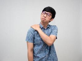 asiatisk manlig anställd ha på sig glasögon känner ont hans axel från hård arbetssätt kontor syndrom isolerat foto