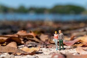 miniatyr- människor, ung älskande innehav händer som de promenad genom en parkera i de falla foto